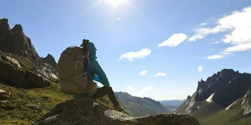 Young man with backpack staring at the wilderness while attending a wilderness program.